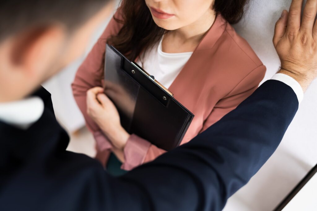 A woman holding a folder while a man's arm is around her shoulder.