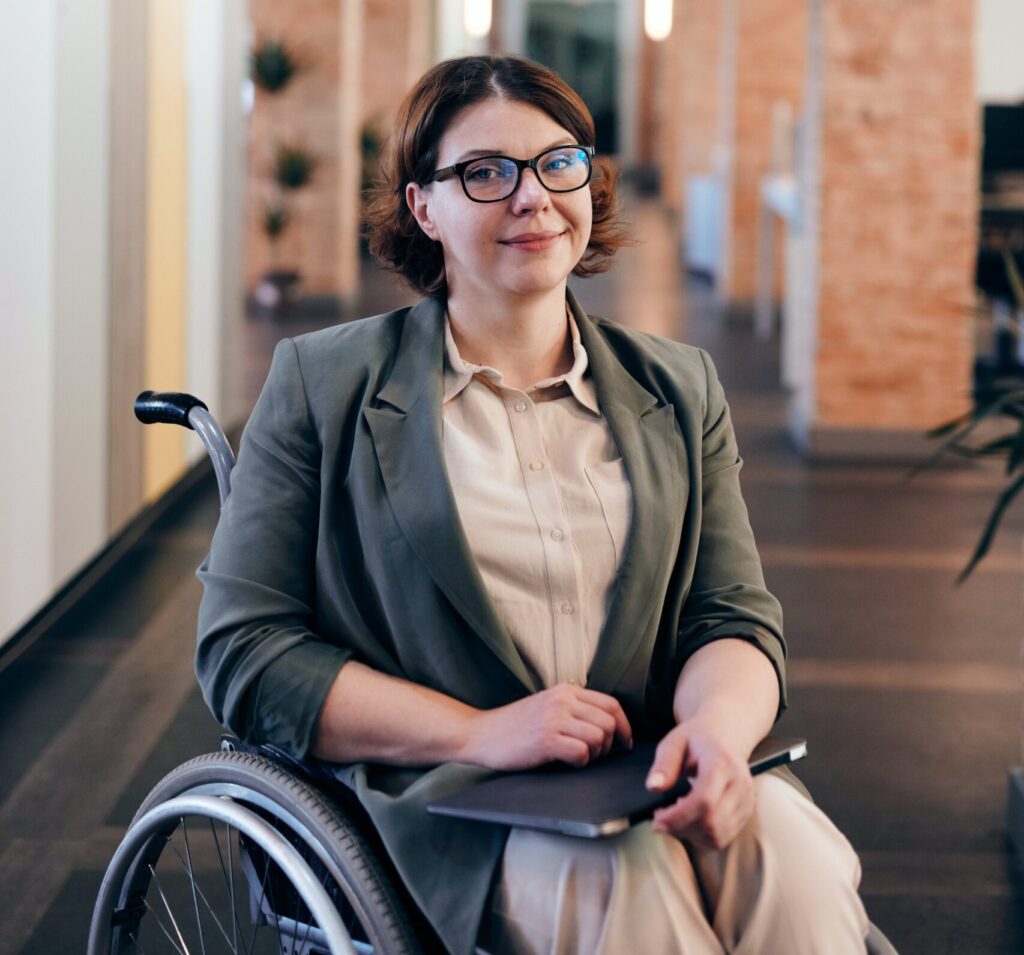 A confident woman in a wheelchair smiling indoors.