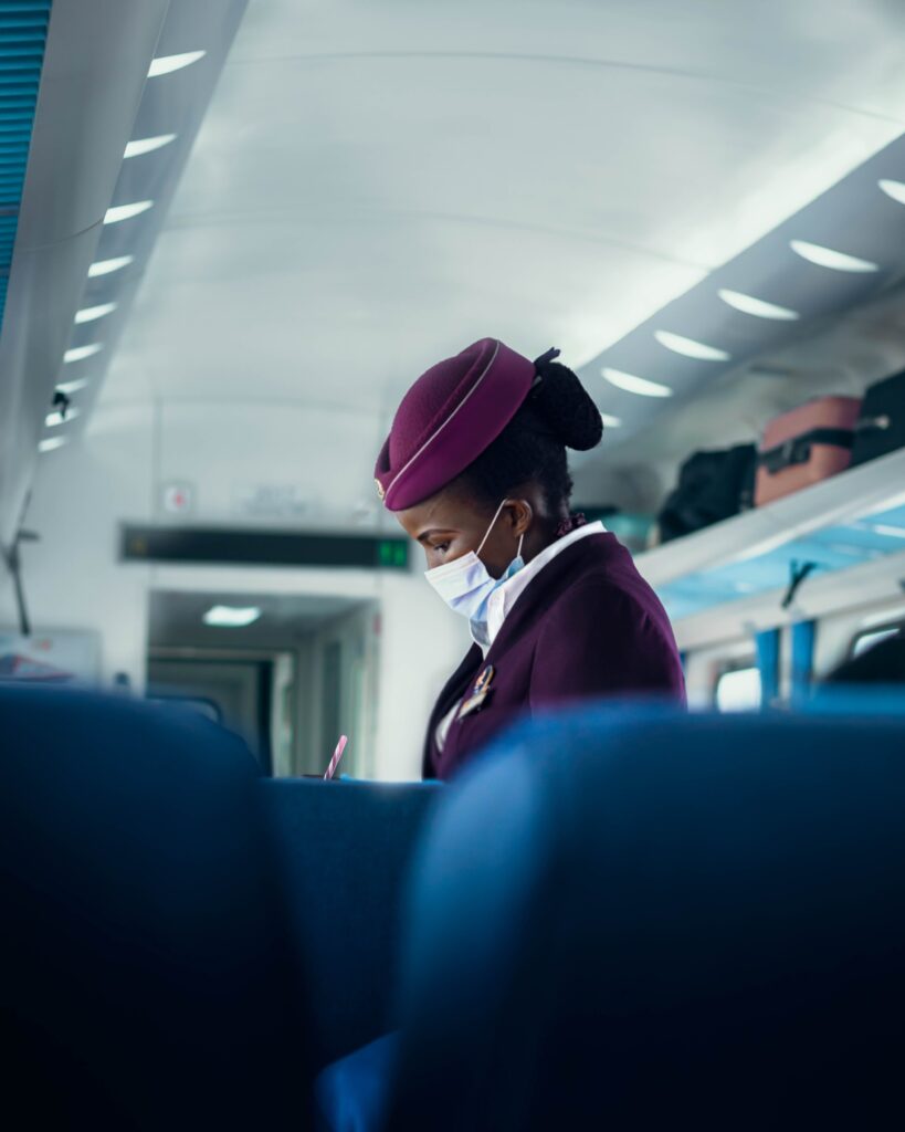 Flight attendant wearing a mask and uniform inside an airplane.
