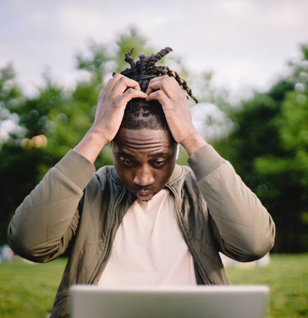 Man concentrating while adjusting his hair outdoors.