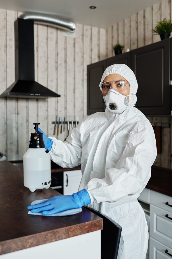 Person in full protective gear disinfecting a kitchen.