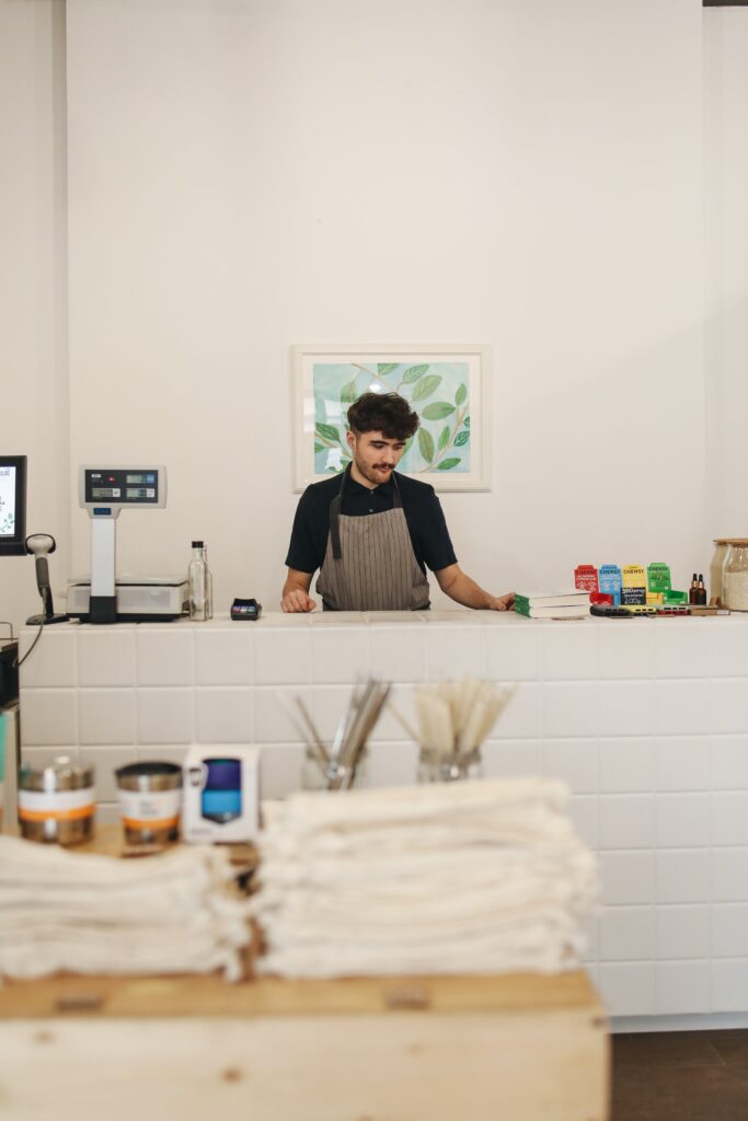 Barista preparing coffee behind a clean, white counter in a minimalist cafe.