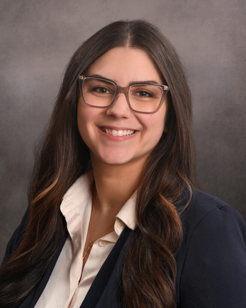 Professional headshot of a smiling woman with glasses and dark hair.
